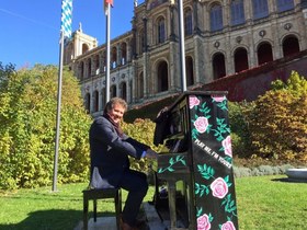 Immobilienmakler Fritz Osterried am Klavier vor dem Maximilianeum in München